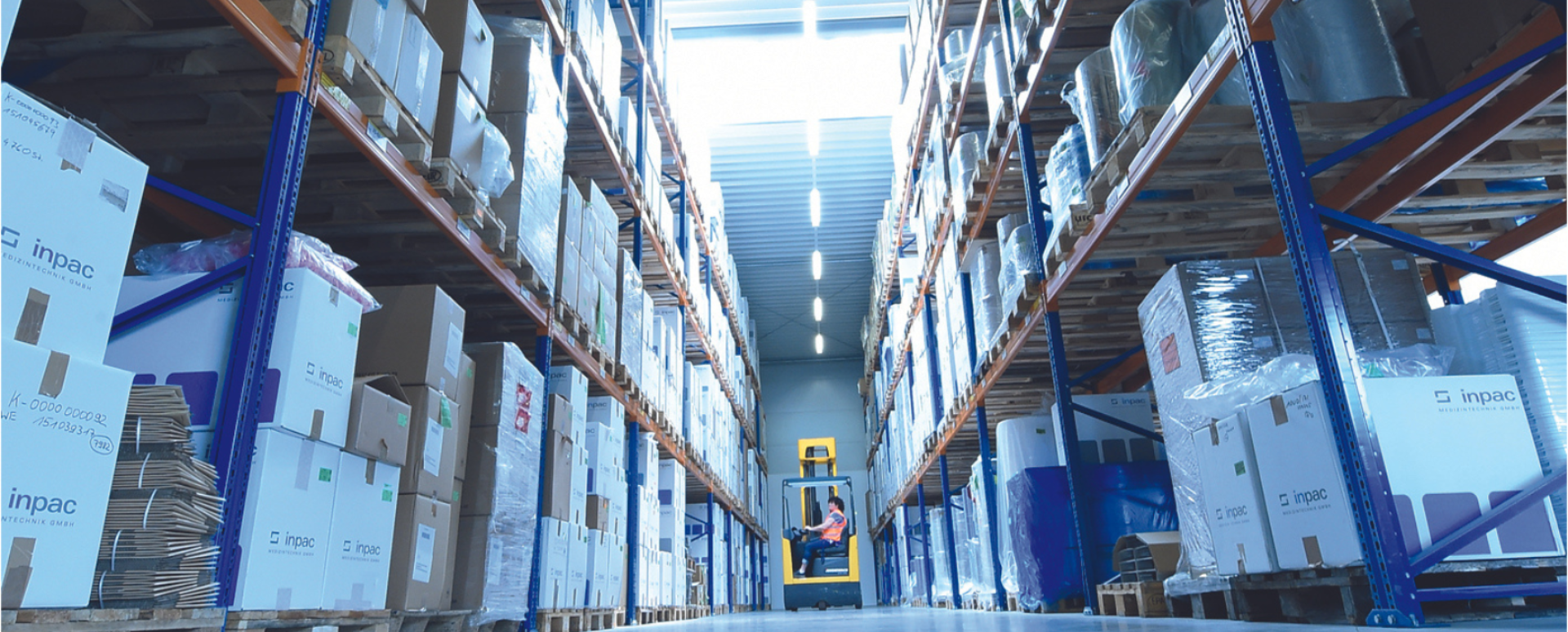 Image d'un garçon conduisant des charges dans un entrepôt avec des produits emballés et prêts à être expédiés.