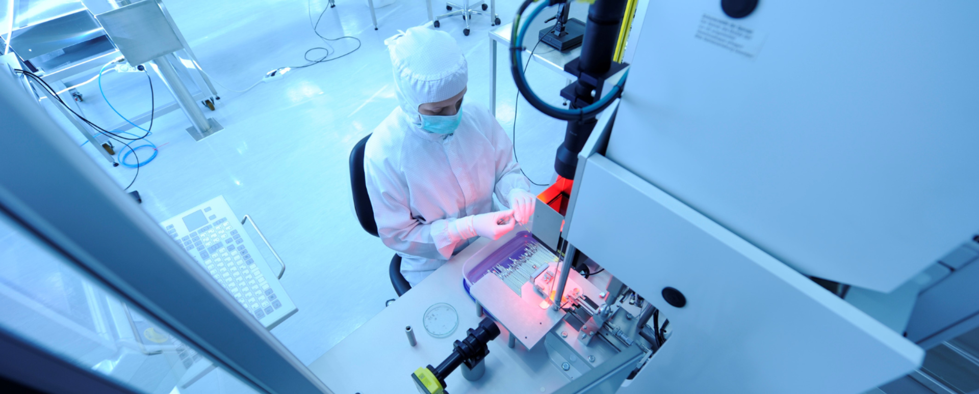 femme en laboratoire avec blouse, bonnet, masque et gants utilisant les machines dans un laboratoire stérile et isolé